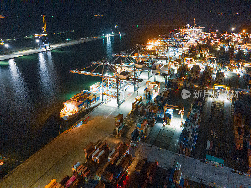 鸟瞰图/一艘大型货船正在通过一个装载货物的港口，装载集装箱运往泰国首都曼谷市东南亚的龙珠港
